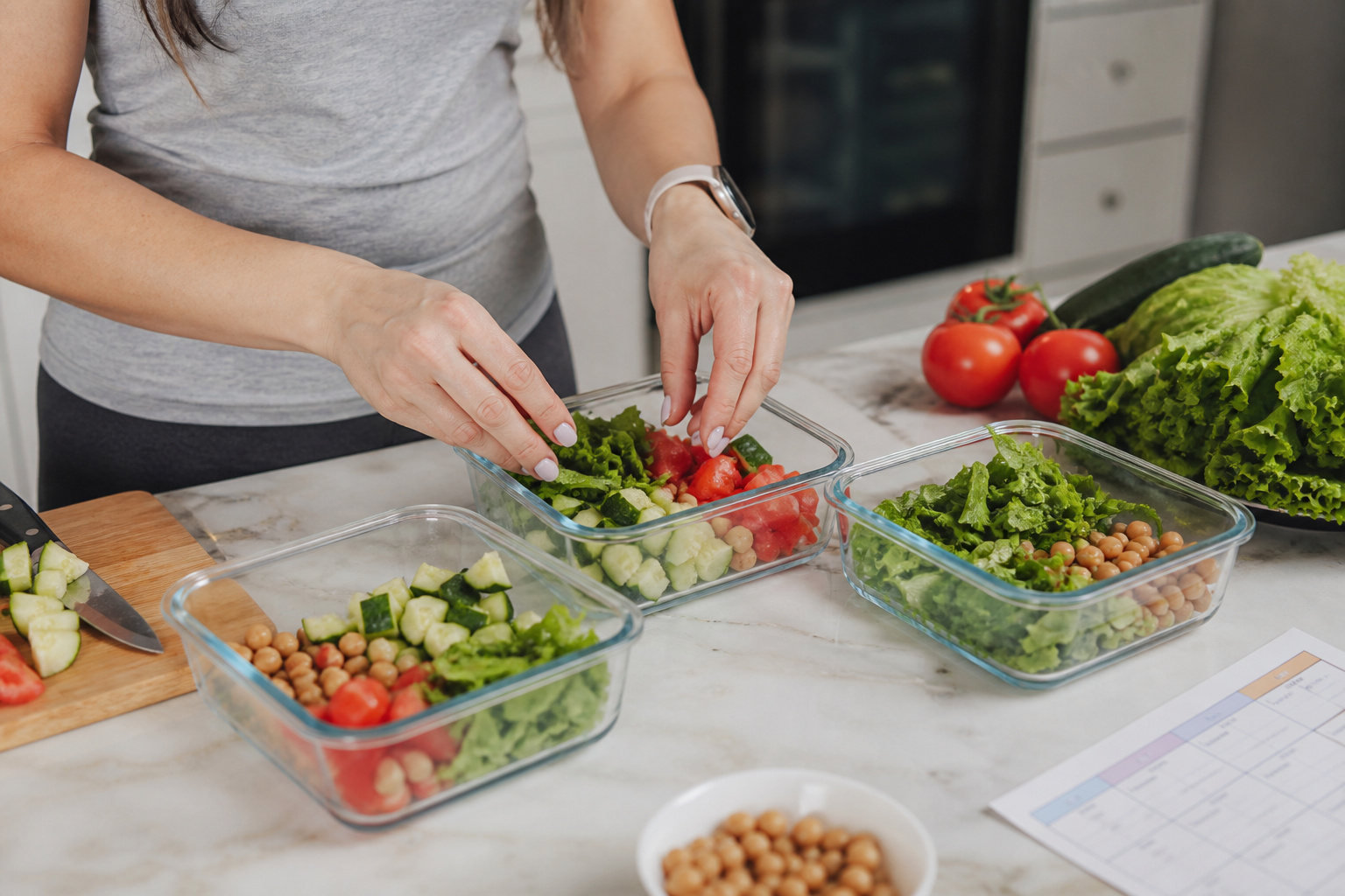 Mujer preparando tuppers con verduras frescas y legumbres para la semana